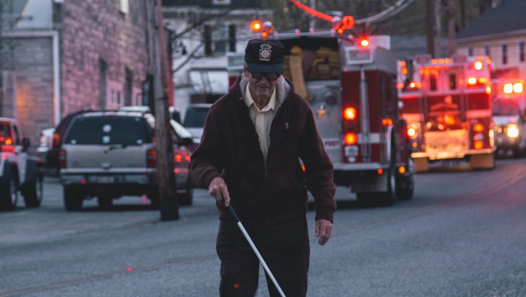 blind person walking away from fire engines